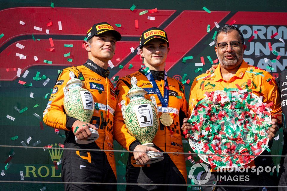Lando Norris, Đội McLaren F1, vị trí thứ 2, Oscar Piastri, Đội McLaren F1, vị trí thứ 1, đại biểu trao cúp McLaren với các cúp trên bục vinh quang