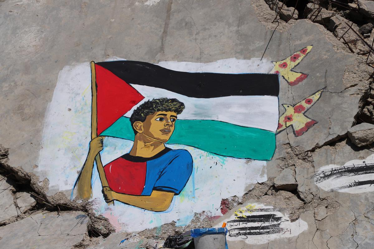 Một bức tranh tường do các nghệ sĩ Palestine vẽ mô tả Lamine Yamal, người vẫy cờ Palestine trong cuộc diễu hành chiến thắng La Liga của Barcelona, ​​​​trên đống đổ nát của các tòa nhà bị phá hủy trong chiến tranh, tại trại tị nạn Shati (Bãi biển) ở Thành phố Gaza hôm thứ Tư.